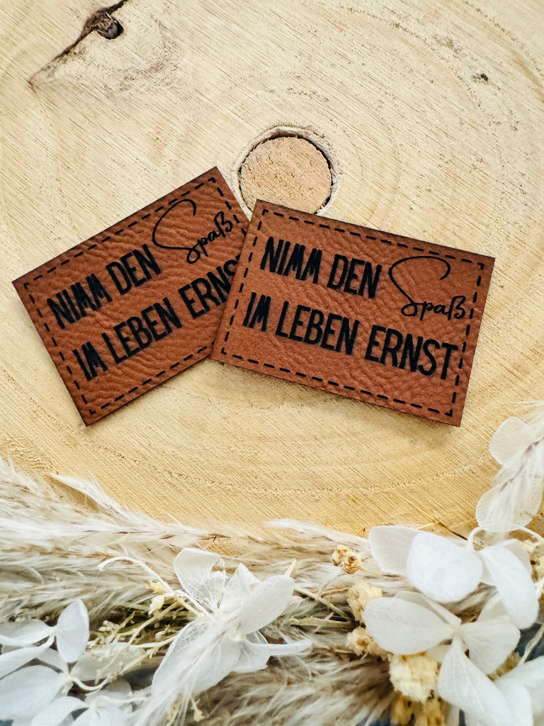 superweiches braunes Kunstlederlabel mit dem Spruch Nimm den Spaß im Leben ernst