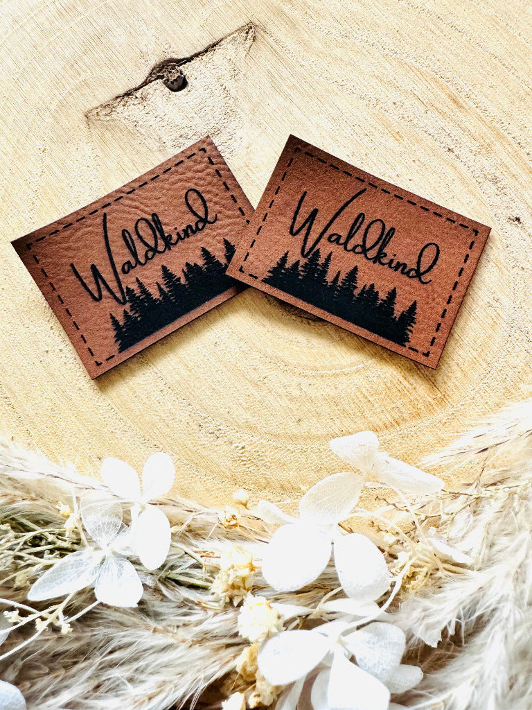 superweiches braunes Kunstlederlabel mit dem Spruch Waldkind und einer Waldsilhouette abgebildet