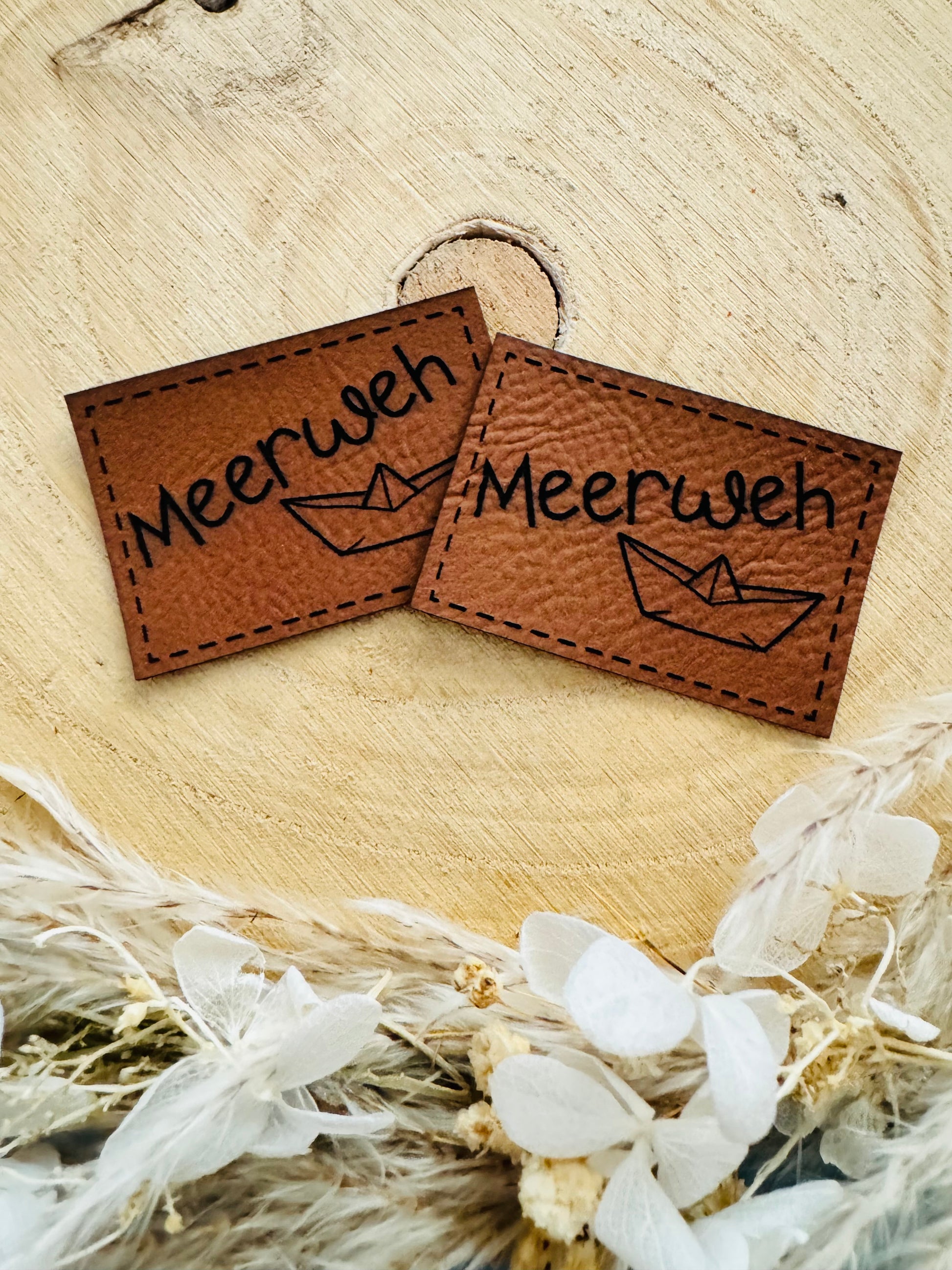 braunes Kunstlederlabel mit dem Spruch Meerweh und einem kleinen Papierschiffchen