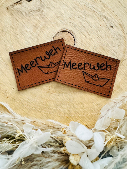 braunes Kunstlederlabel mit dem Spruch Meerweh und einem kleinen Papierschiffchen