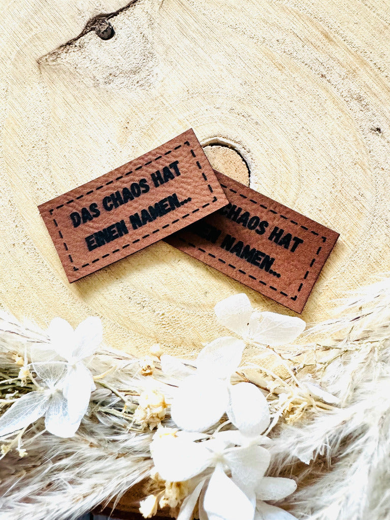 superweiches braunes Kunstlederlabel mit dem Spruch Das Chaos hat einen Namen Punkt Punkt Punkt