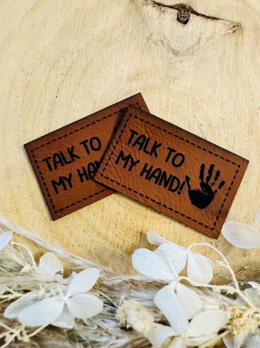 superweiches braunes Kunstlederlabel mit dem Spruch Talk to myHand Ausrufezeichen und einer abgebildeten Handfläche