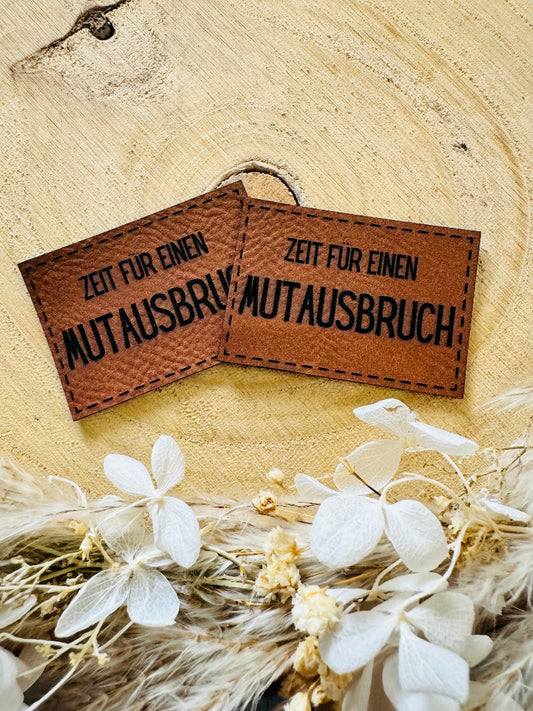 braunes Kunstlederlabel mit dem Spruch Zeit für einen Mutausbruch
