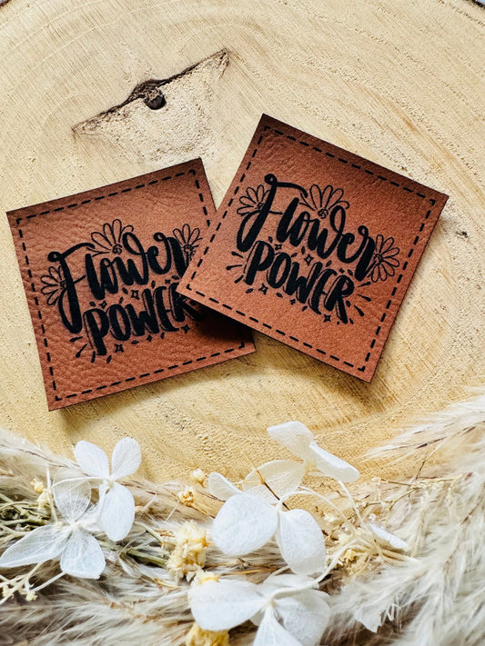 superweiches braunes Kunstlederlabel mit dem Spruch Flower Power umrahmt von Blüten