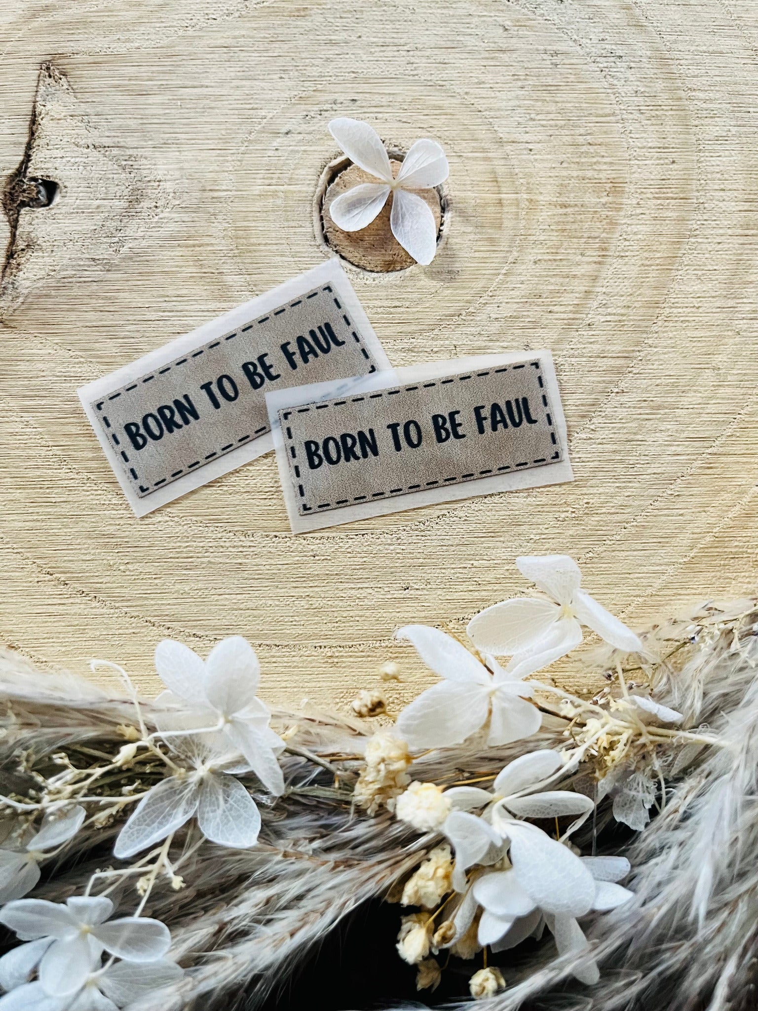 hellgraues Bügellabel mit dem Spruch Born to be Faul in schwarzer schrift