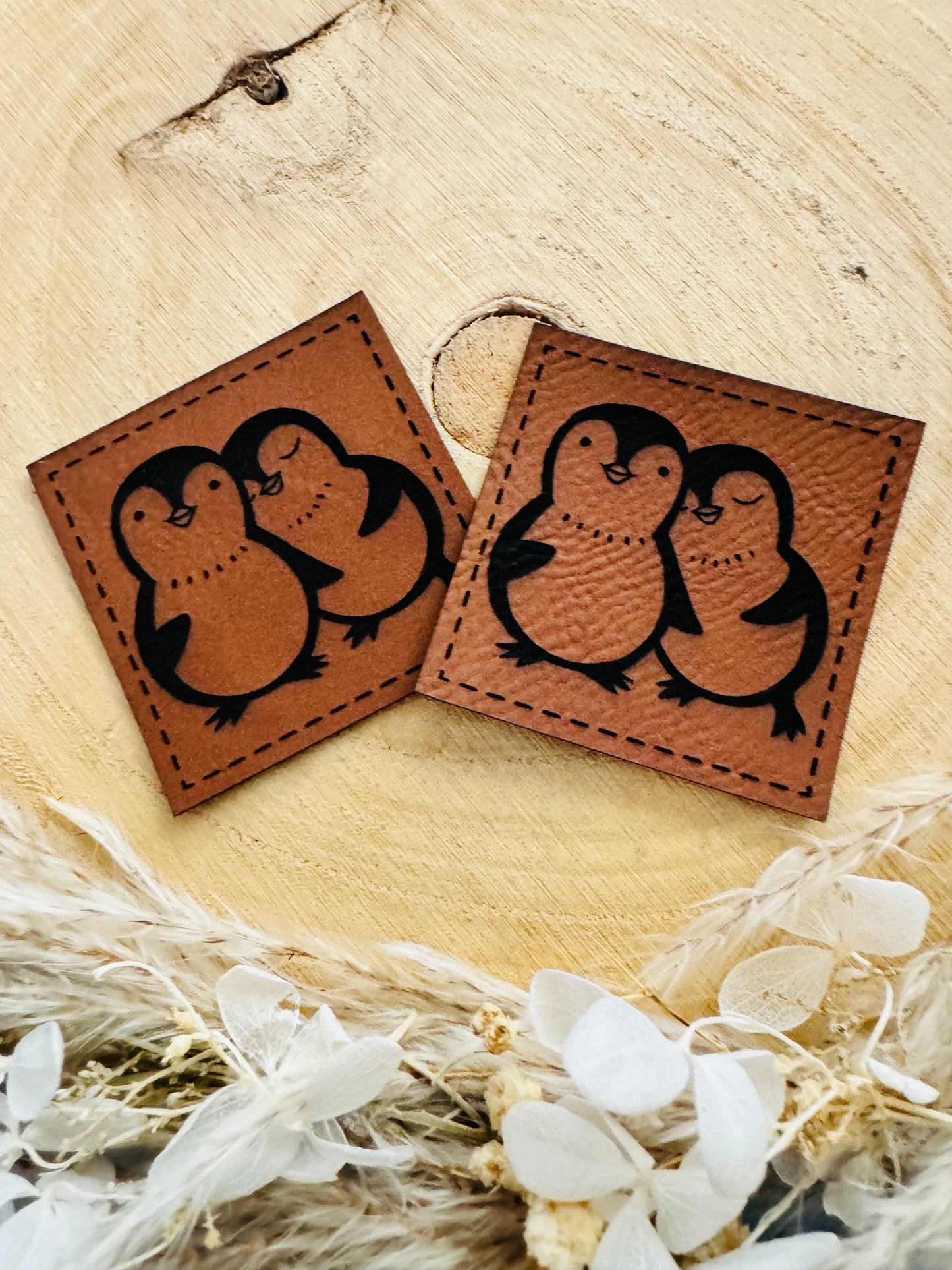 braunes Kunstlederlabel mit zwei kuschelnden kleinen Pinguinen