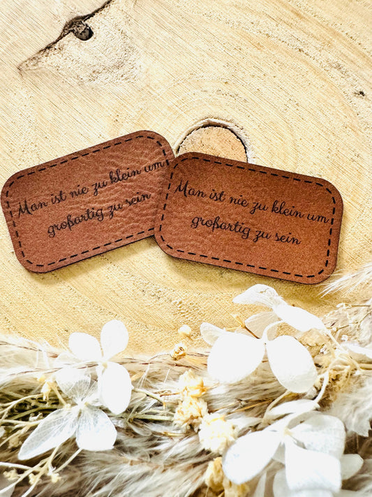 superweiches braunes Kunstlederlabel mit dem Spruch Man ist nie zu klein um großartig zu sein in schwarzer Schrift