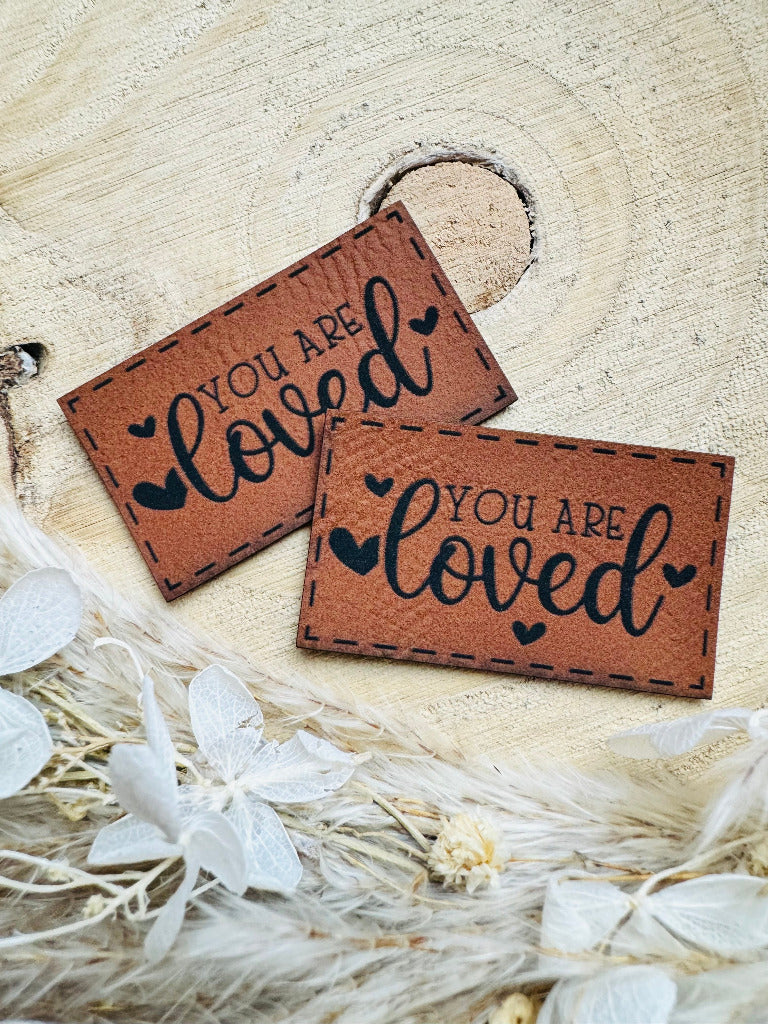 superweiches braunes Kunstlederlabel mit dem Spruch You are loved mit kleinen Herzchen in schwarz