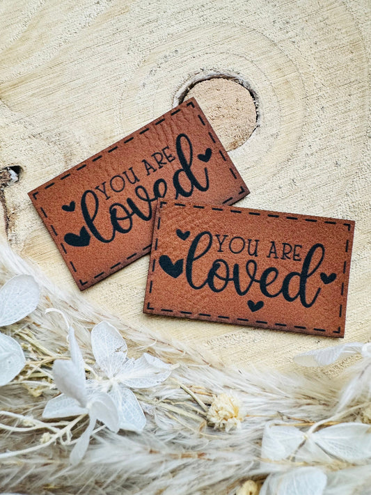 superweiches braunes Kunstlederlabel mit dem Spruch You are loved mit kleinen Herzchen in schwarz