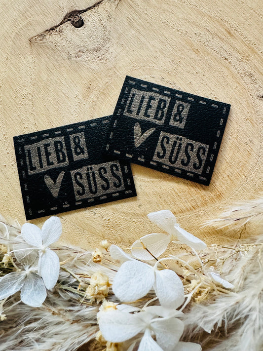 schwarzes PU-Label mit dem Spruch Lieb und Süss in silberner Schrift