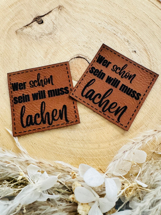 superweiches braunes Kunstlederlabel mit dem Spruch Wer schön sein will muss lachen