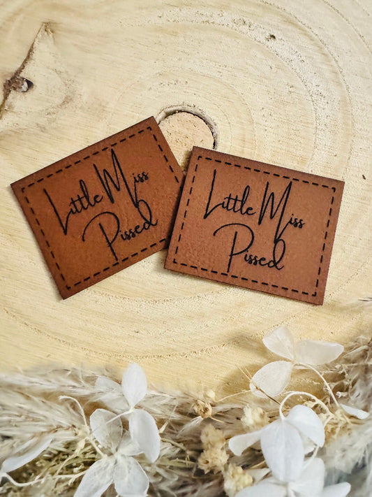 superweiches braunes Kunstlederlabel mit dem Spruch Little Miss Pissed in schöner schwarzer Schrift