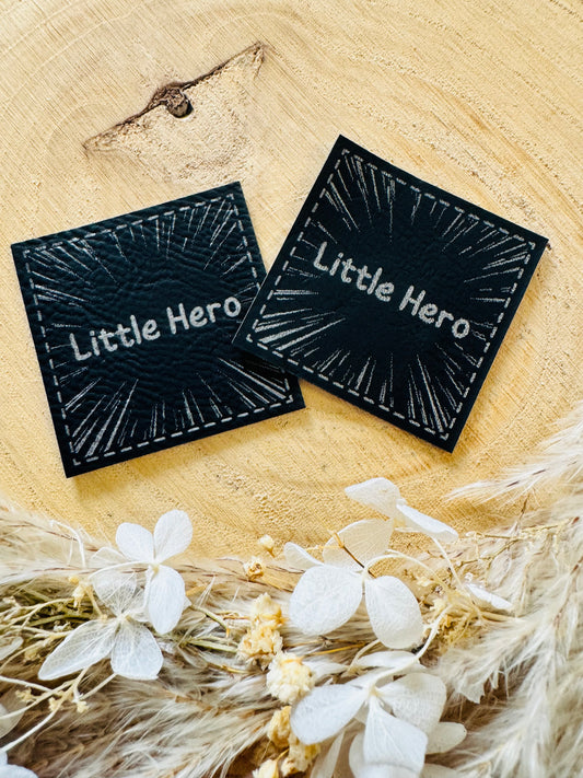 schwarzes kunstlederlabel mit dem spruch little hero