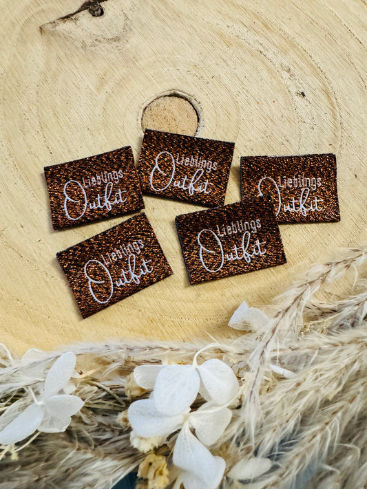 bronzen glitzerndes  Weblabel mit dem Spruch Lieblings Outfit in weisser Schrift