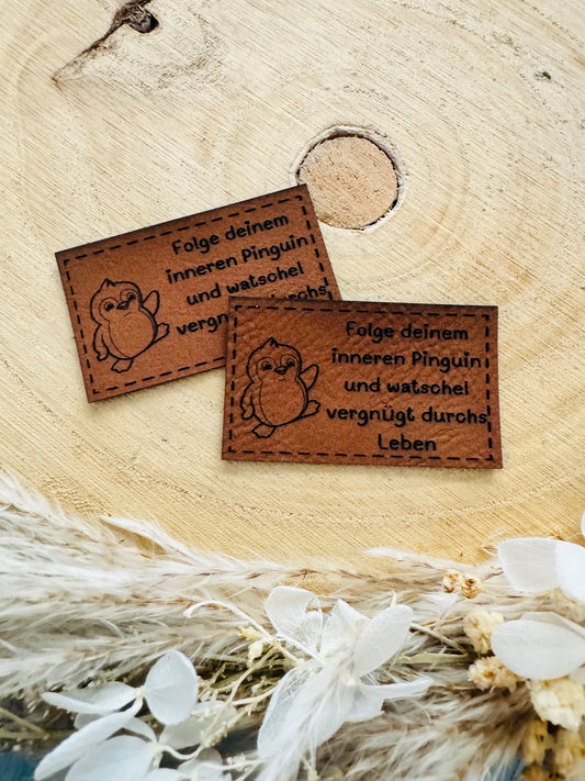 braunes Kunstlederlabel mit dem Spruch Folge deinem inneren Pinguin und watschel vergnügt durchs Leben