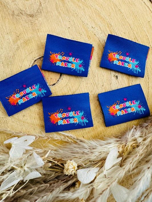 blaues Weblabel mit Spruch Trouble Maker in bunter Schrift und Farbklecksen