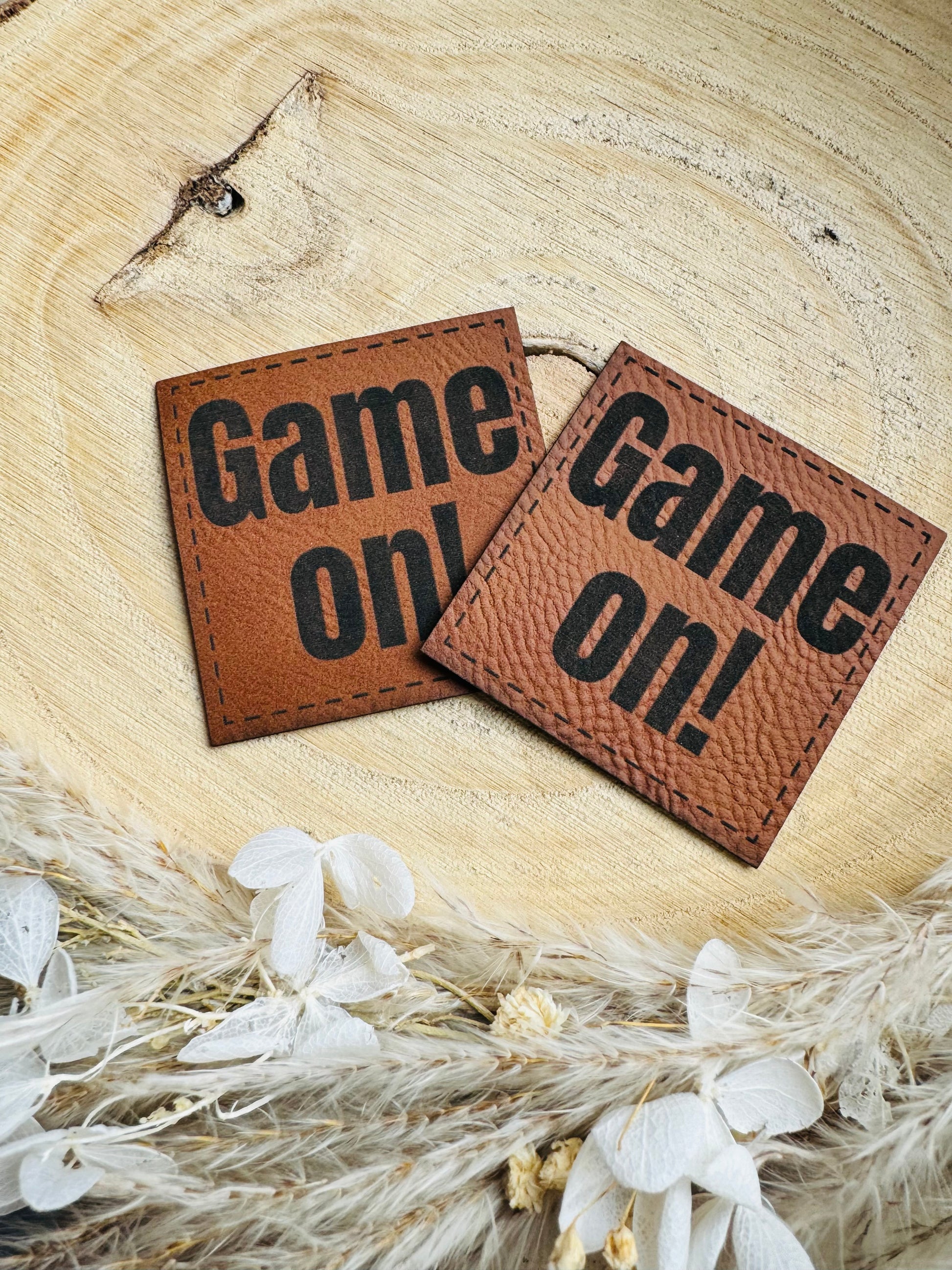 braunes Kunstlederlabel mit dem Spruch Game on Ausrufezeichen in schwarzer Schrift