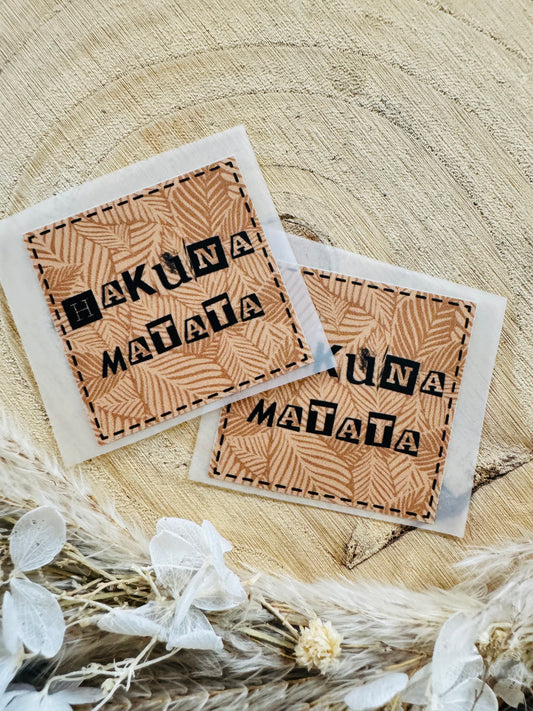 braun gemustertes Bügellabel Etikett mit dem Spruch Hakuna Matata in schwarzer Schrift