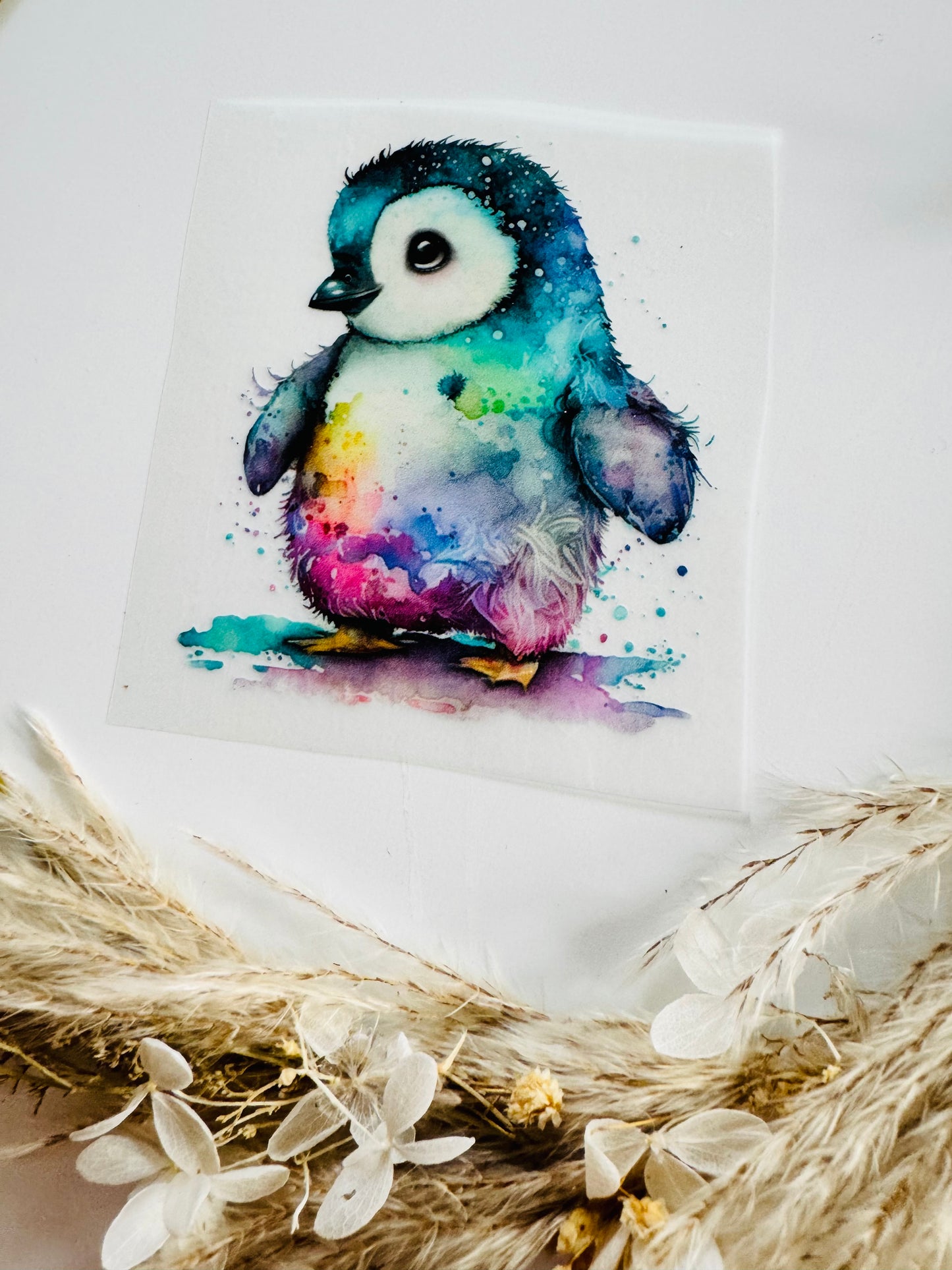 im Dunkeln leuchtendes Bügelbild mit einem kleinen Pinguin in bunten Aquarell Farben