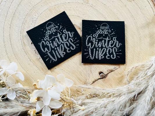 schwarzes Kunstlederlabel mit einem Schneemann und dem Spruch Winter Vibes in silberner Schrift