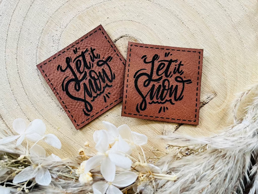 braunes Kunstlederlabel mit dem Spruch Let it Snow