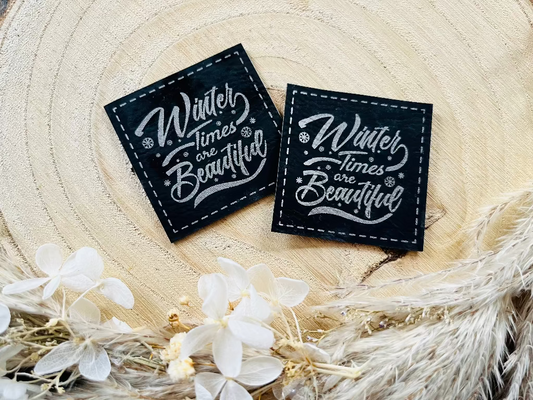 schwarzes Kunstlederlabel mit dem Spruch Winter Times are beautyful in silberner Schrift