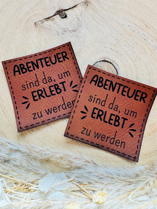 braunes PU-Label mit dem Spruch Abenteuer sind da, um ERLEBT zu werden