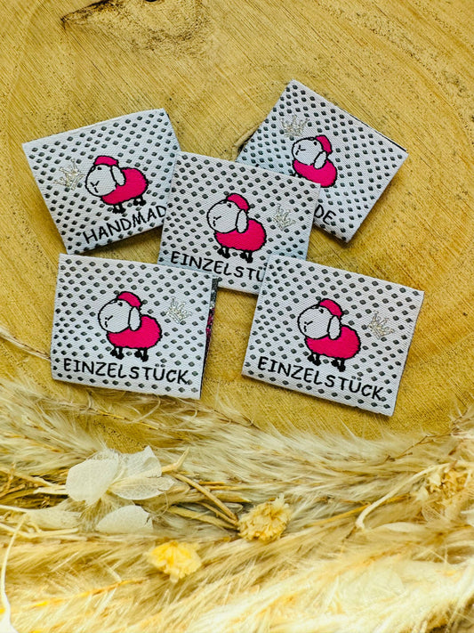 weiss gepunktetes Weblabel mit einem kleinen rosa Schäfchen und den Sprüchen Handmade und Einzelstück