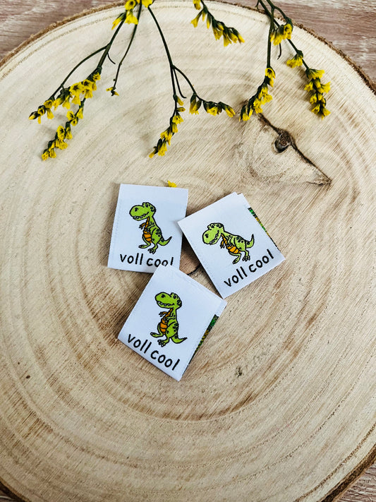 weisses Weblabel mit einem kleinen grünen Dino und darunter der Spruch voll cool in schwarzer Schrift