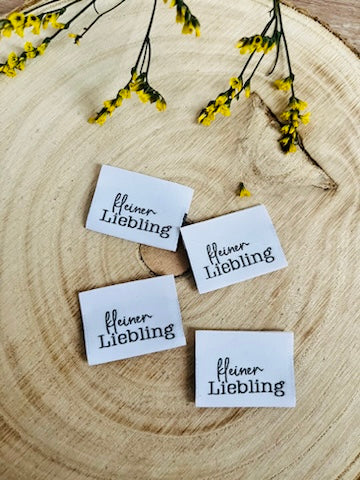 weisses Weblabel mit Aufschrift kleiner Liebling in schwarzer Schrift