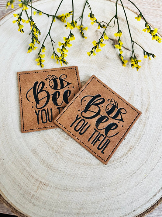 braunes kunstlederlabel mit dem spruch bee you tiful und einer kleinen biene abgebildet