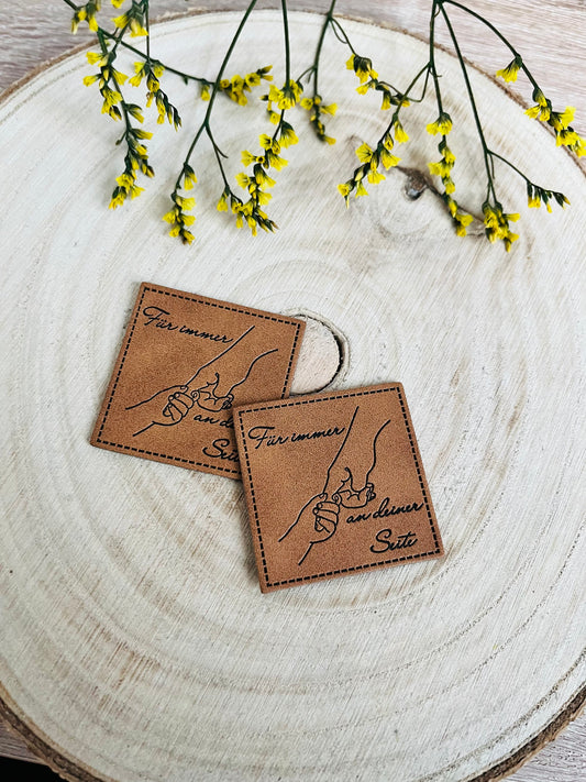 braunes kunstlederlabel mit dem spruch für immer an deiner seite und zwei sich berührende Hände abgebildet