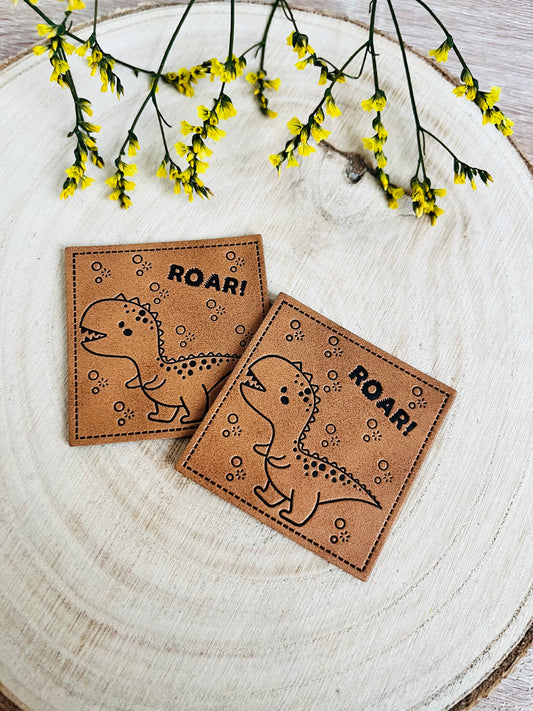 braunes kunstlederlabel mit dem spruch roar und einem kleinen dino abgebildet