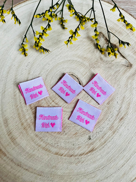 weisses Weblabel mit dem Spruch Handmade with in rosa Schrift und einem rosa herzen