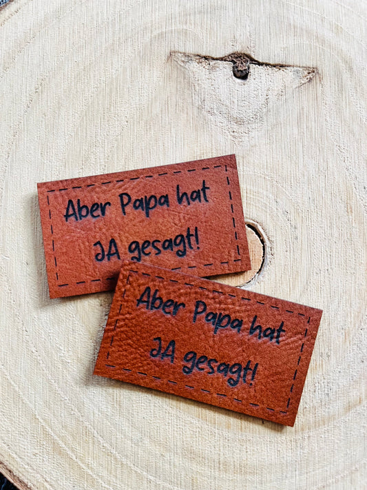 braunes Kunstlederlabel mit dem Spruch Aber Papa hat JA gesagt Ausrufezeichen
