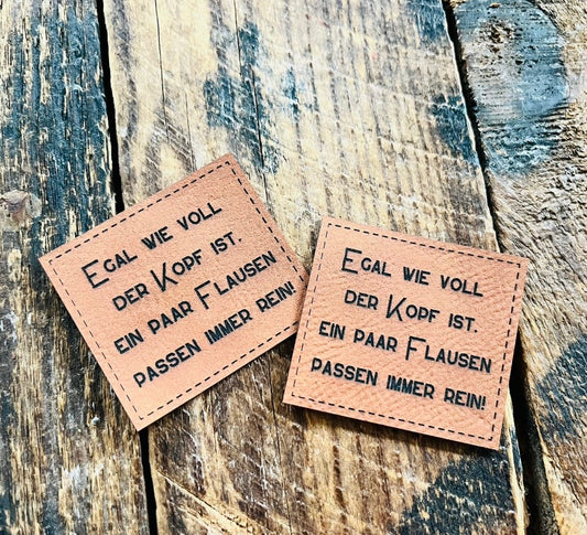 braunes Kunstlederlabel mit dem Spruch Egal wie voll der Kopf ist. Ein Paar Flausen passen mmer rein Ausrufezeichen