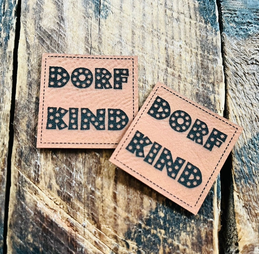 braunes Kunstlederlabel mit dem Spruch DORF KIND