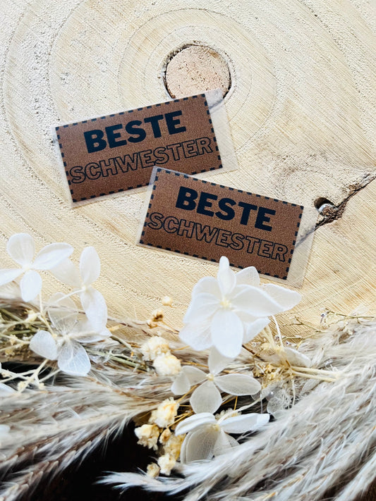 braunes Bügellabel mit dem Spruch beste Schwester in schwarzer Schrift