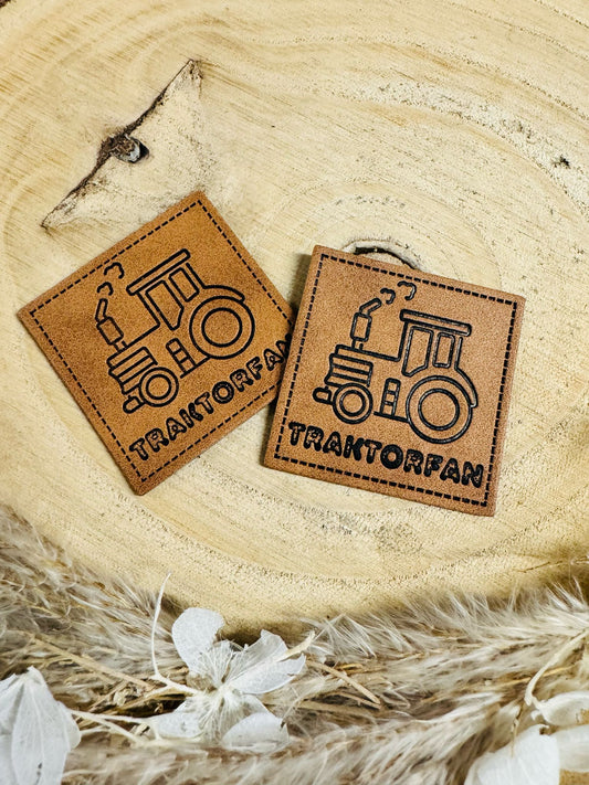 braunes Kunstlederlabel mit einem Traktor abgebildet und dem Wort Traktorfan