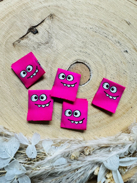 gewebtes Label in Pink mit einem kleinen Monstergesicht
