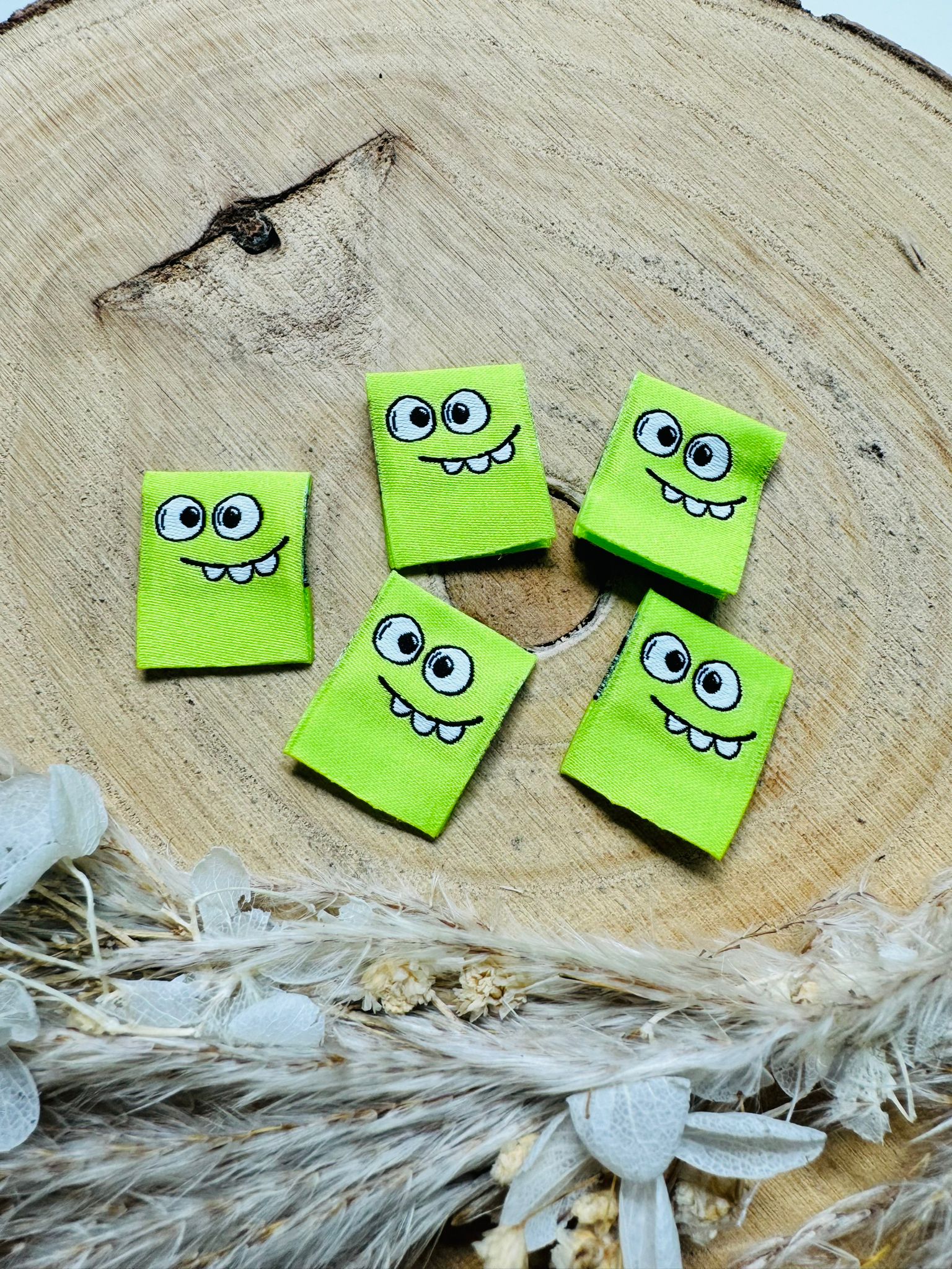 gewebtes grünes Label mit einem kleinen Monstergesicht 
