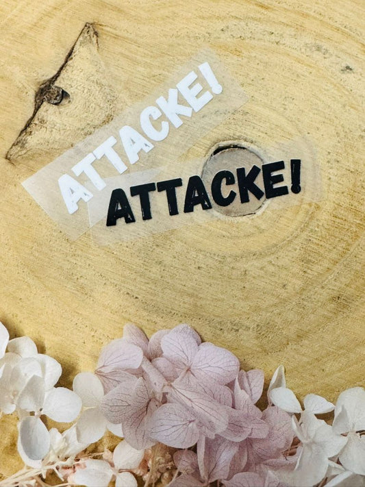aufbügelbares Label mit dem Wort Attacke Ausrufezeichen in schwarz und weiss