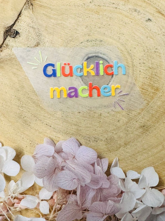 aufbügelbares Label mit dem Spruch Glücklichmacher in bunter Schrift