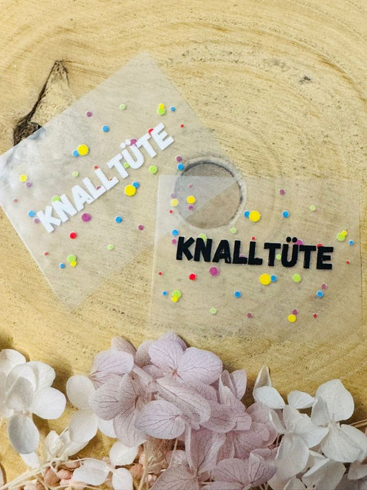 aufbügelbares Label mit dem Spruch Knalltüte in schwarz und weiss mit buntem konfetti
