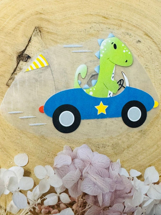 ein tolles Bügelbild aus der Growi Kollektion mit einem Dino in einem blauen Rennauto dargestellt