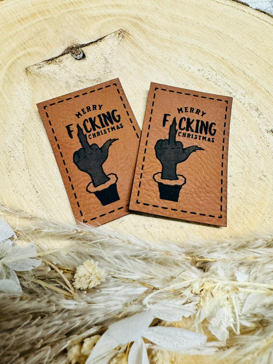 braunes christmas kunstlederlabel mit dem spruch merry fucking christmas und einem stinkefinger