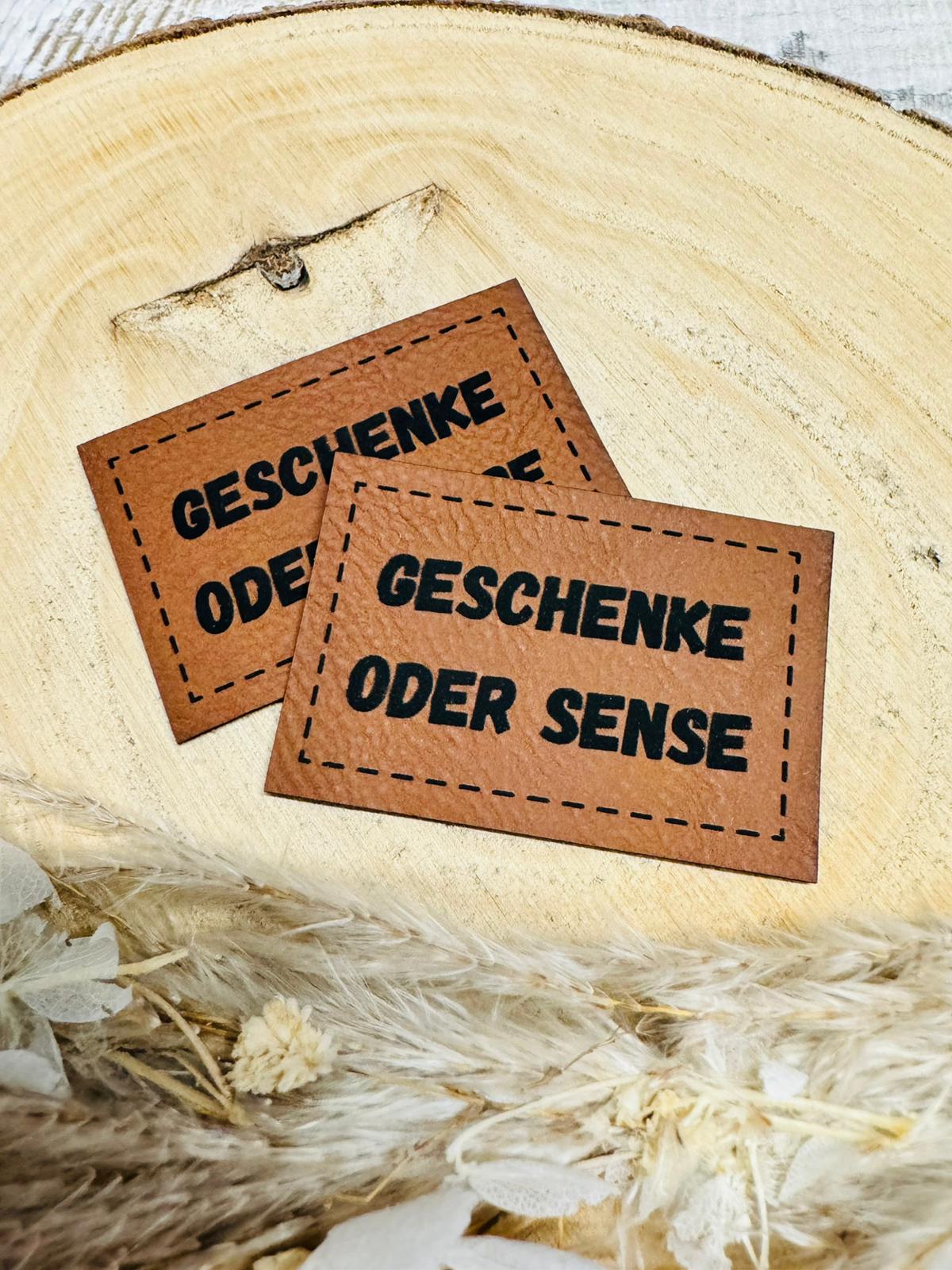 braunes kunstlederlabel mit dem spruch geschenke oder sense