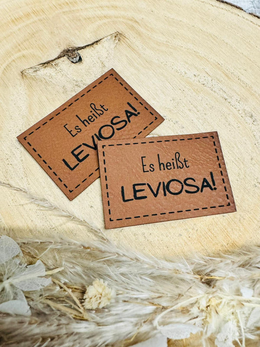 braunes christmas kunstlederlabel mit dem spruch es heißt leviosa ausrufezeichen
