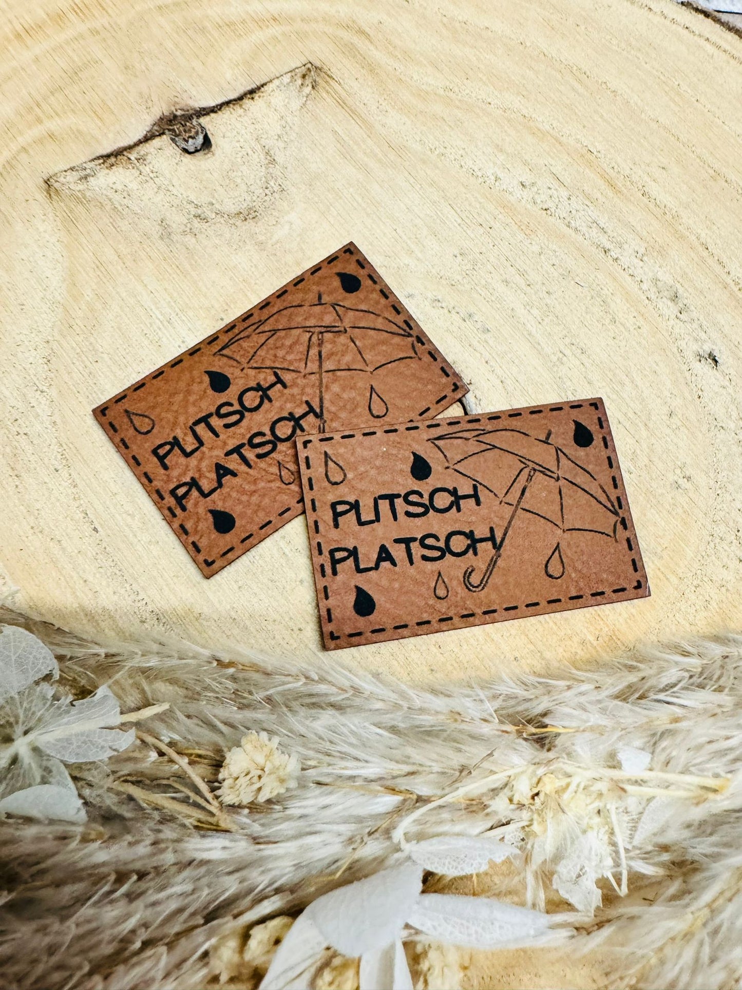 braunes  kunstlederlabel mit dem spruch plitsch platsch und einem regenschirm abgebildet