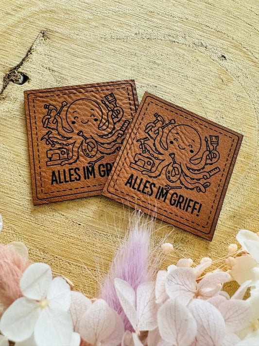 superweiches braunes Kunstleder Label mit dem Spruch Alles im Griff und einem Tintenfisch abgebildet